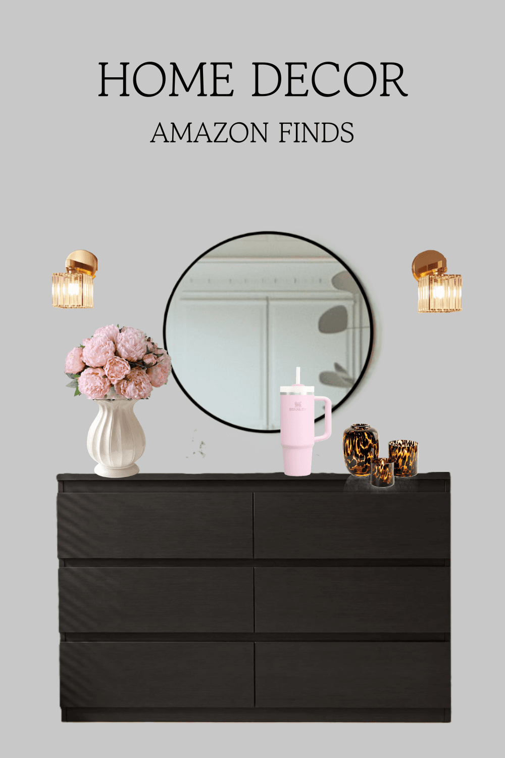 This styled vignette pairs a sleek black dresser with a round black-framed mirror, gold crystal wall sconces, soft pink peonies in a ribbed cream vase, a pink tumbler and leopard-print glass candle holders.